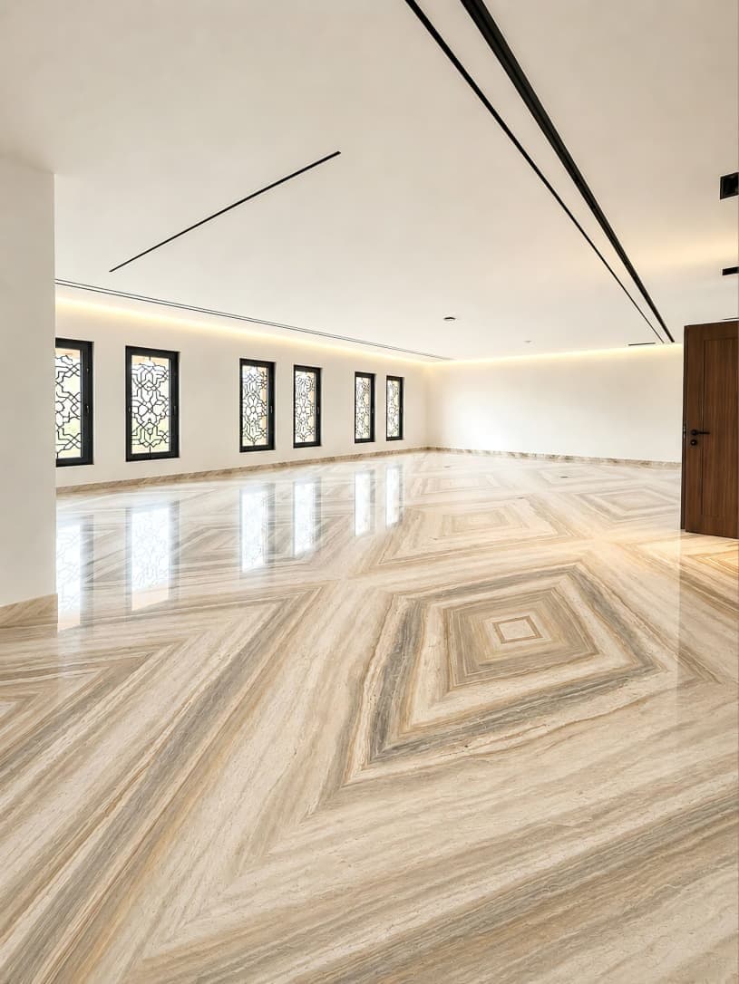 Diamond-pattern travertine floor in a room with arched stained-glass windows