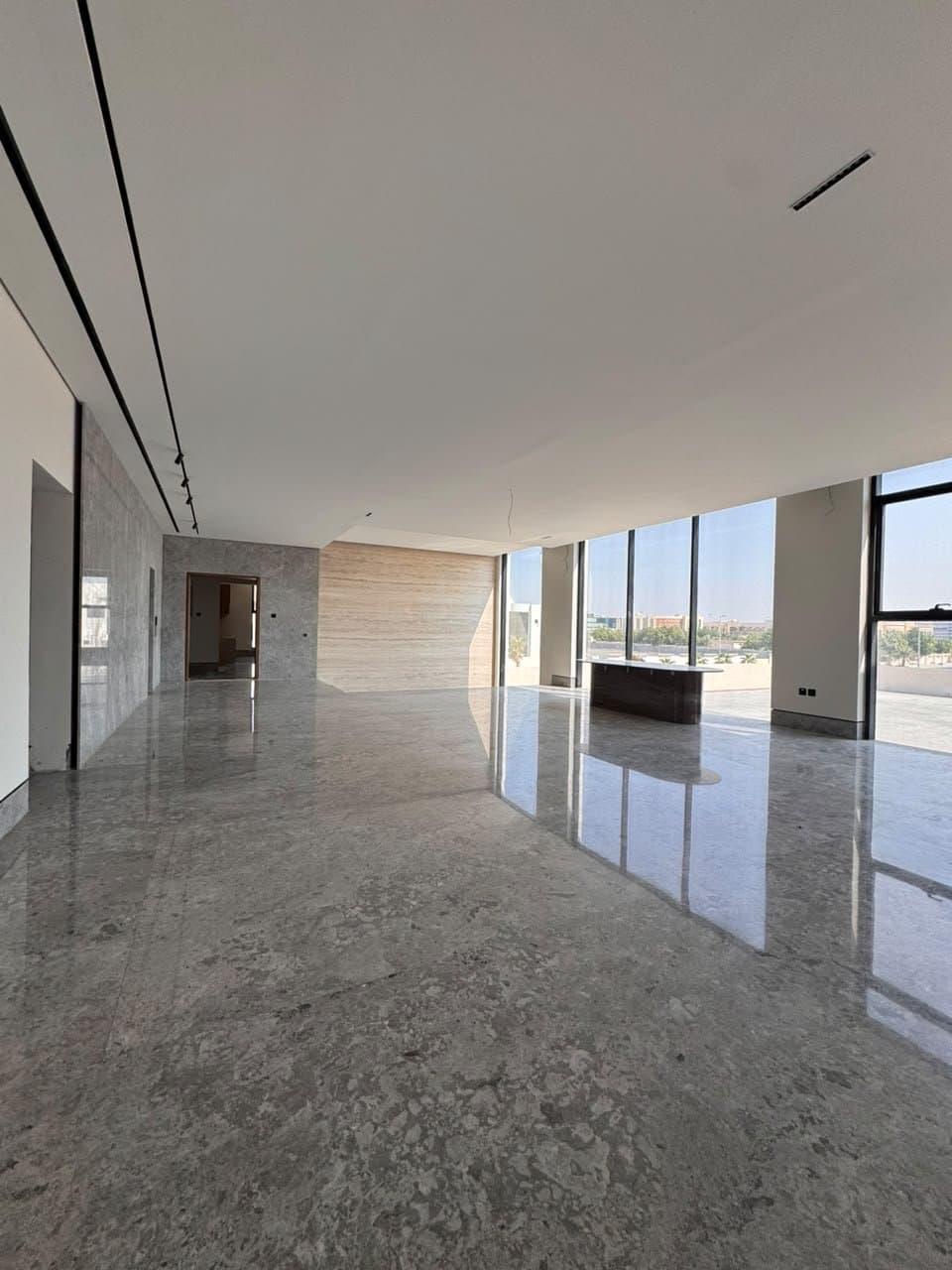 Large-format polished stone floor in an open-plan living space with city views