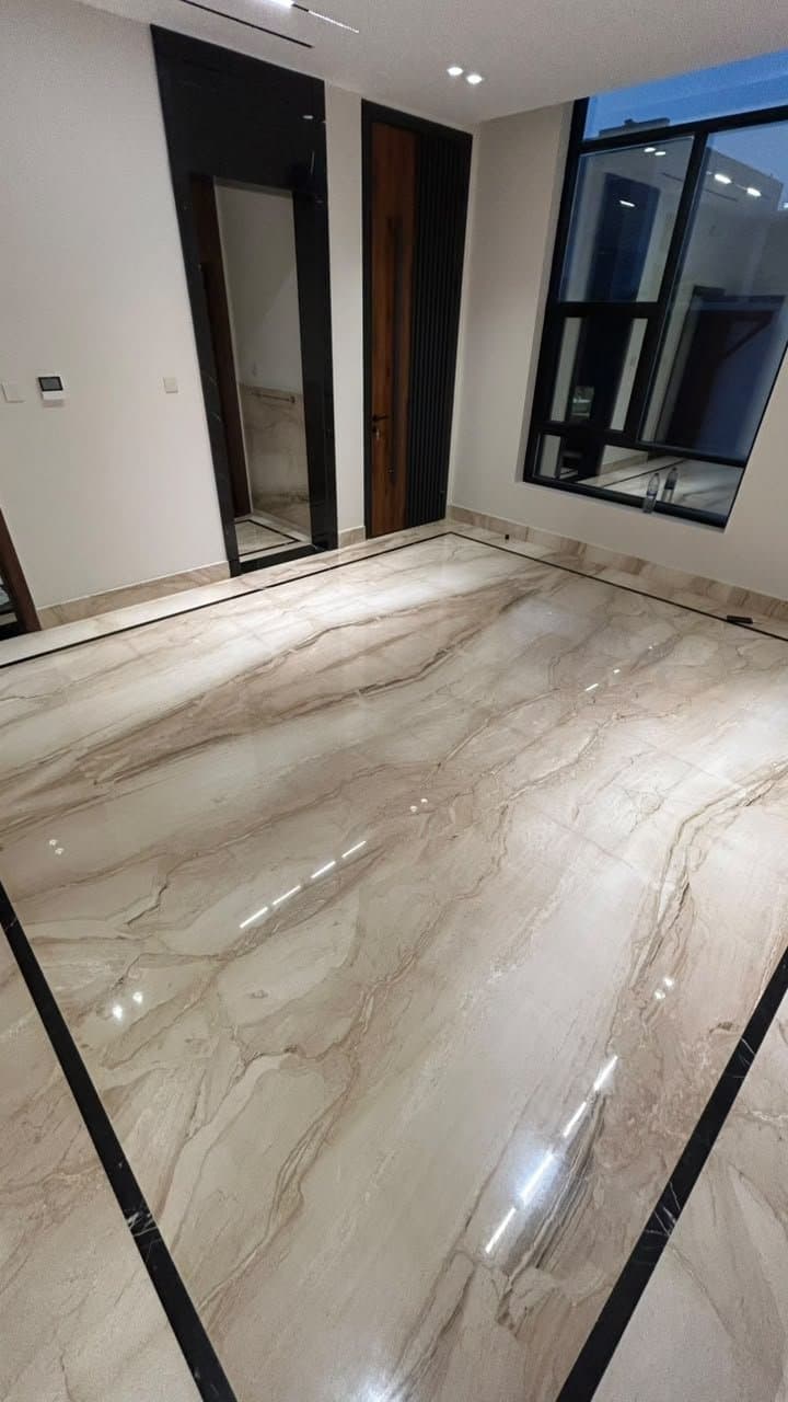Marble flooring with black stone inlay border beside a mirrored wall