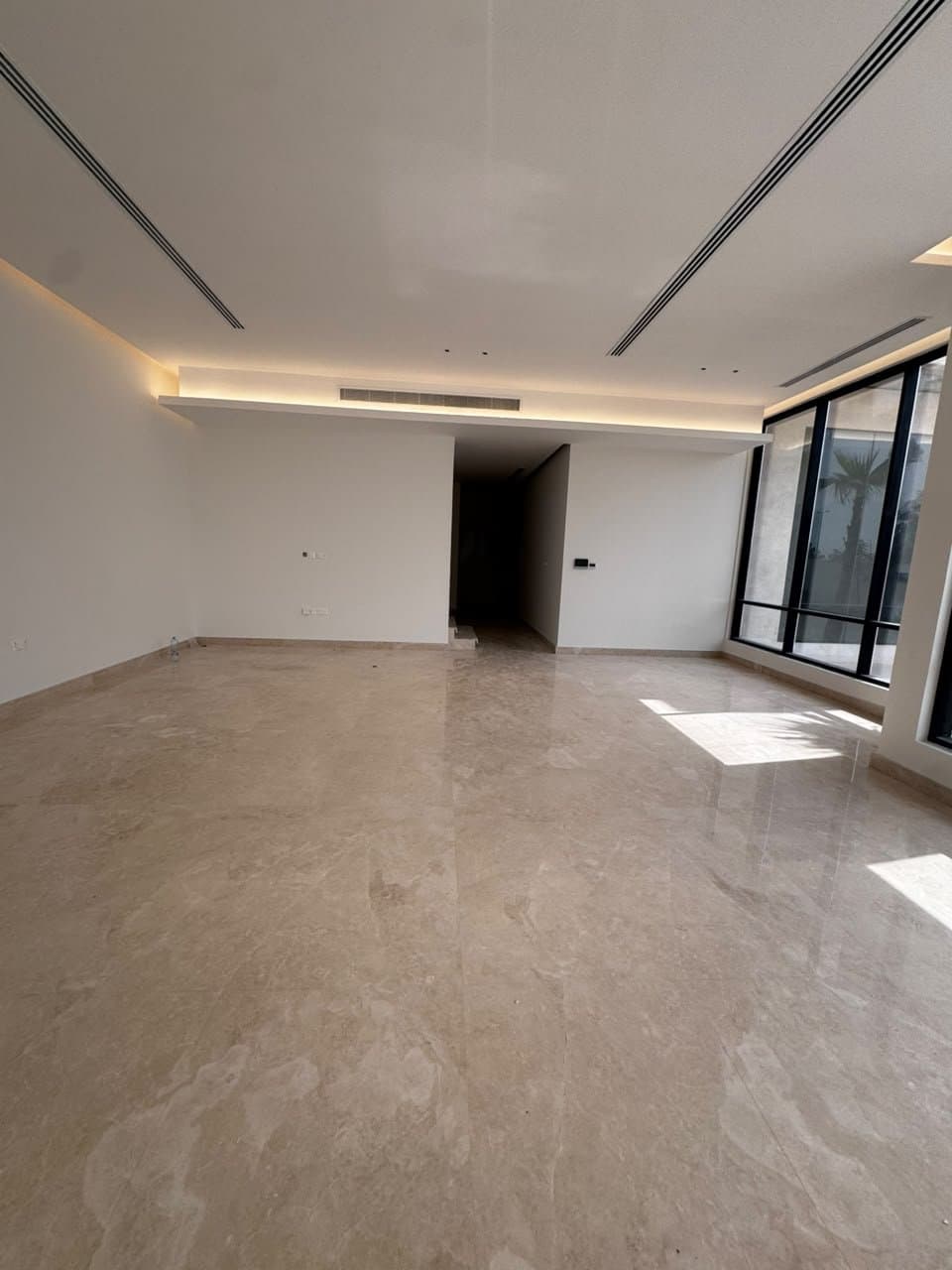 Beige marble flooring in an open-plan living room with floor-to-ceiling windows