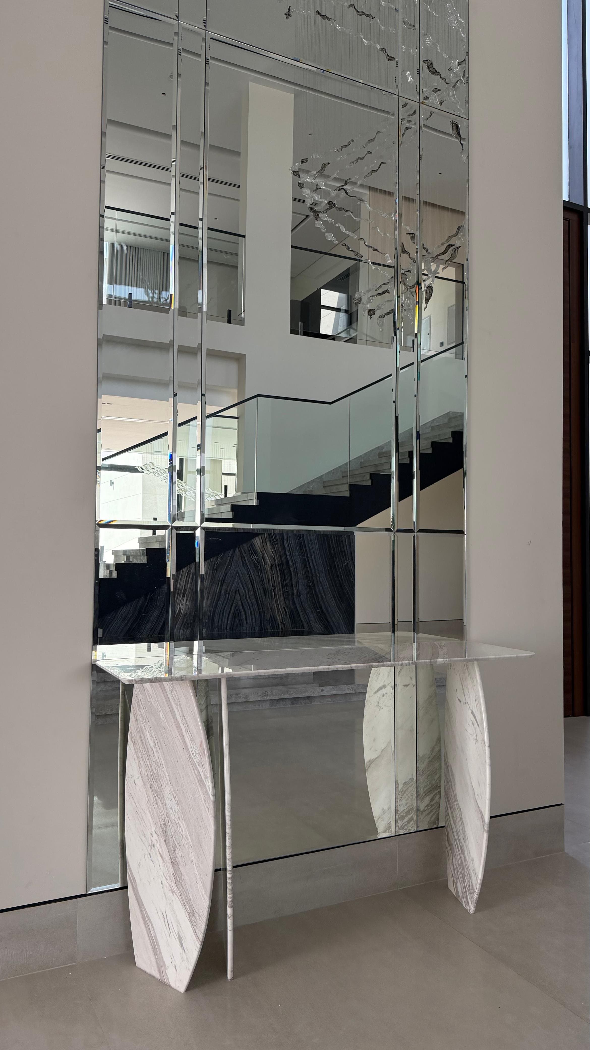 Mirrored console table on marble waterfall legs in a foyer