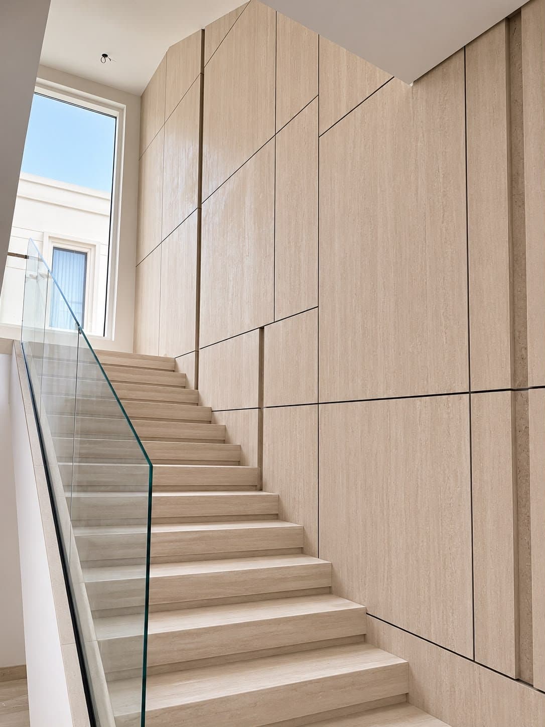 Bookmatched marble flooring in a villa hallway with a staircase beyond