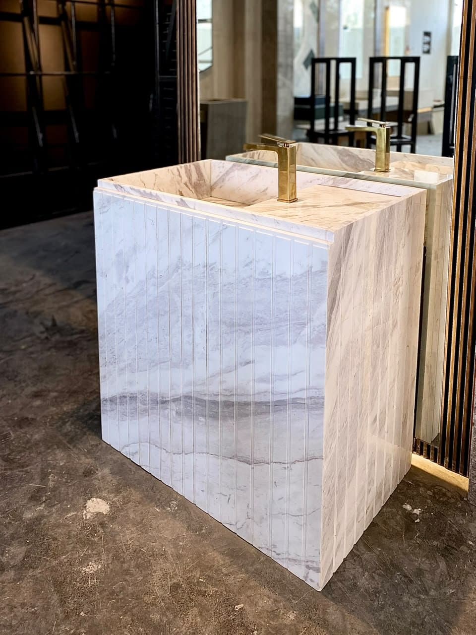 Fluted marble pedestal vessel sink with gold faucet