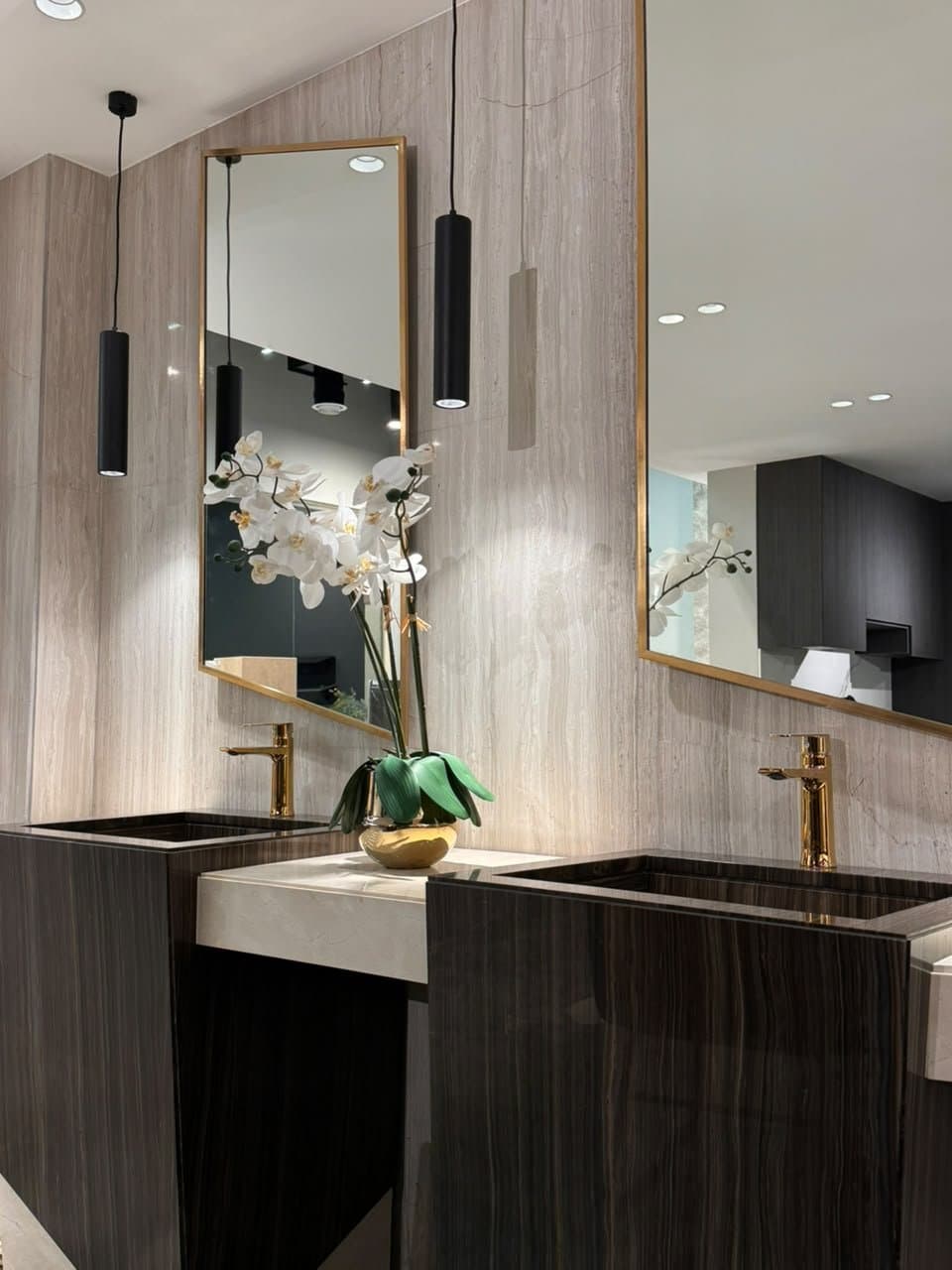 Dark wood-grain stone double vanity with gold-framed mirrors and orchid