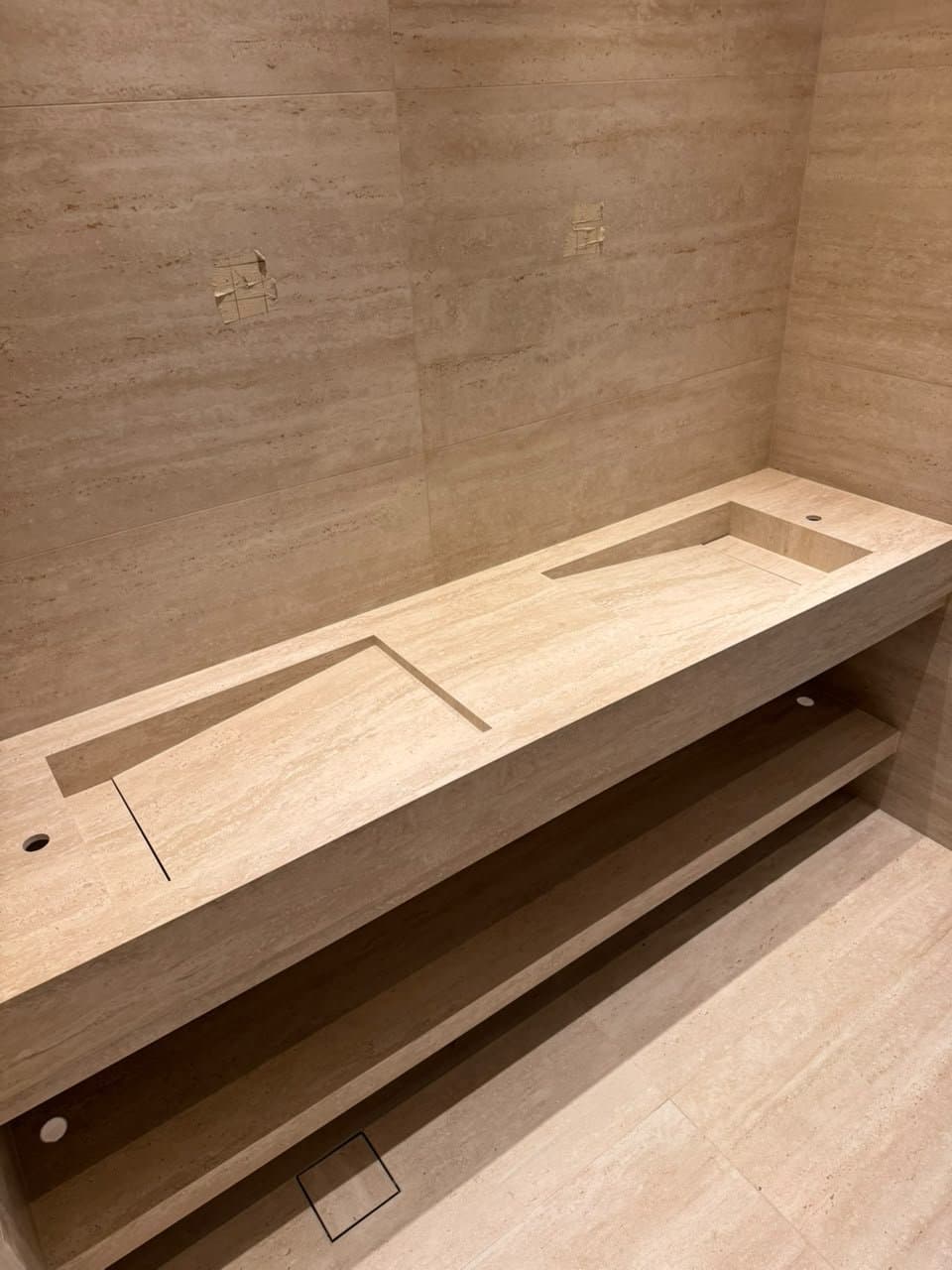 Travertine floating vanity with cutout sink shapes, mid-fabrication