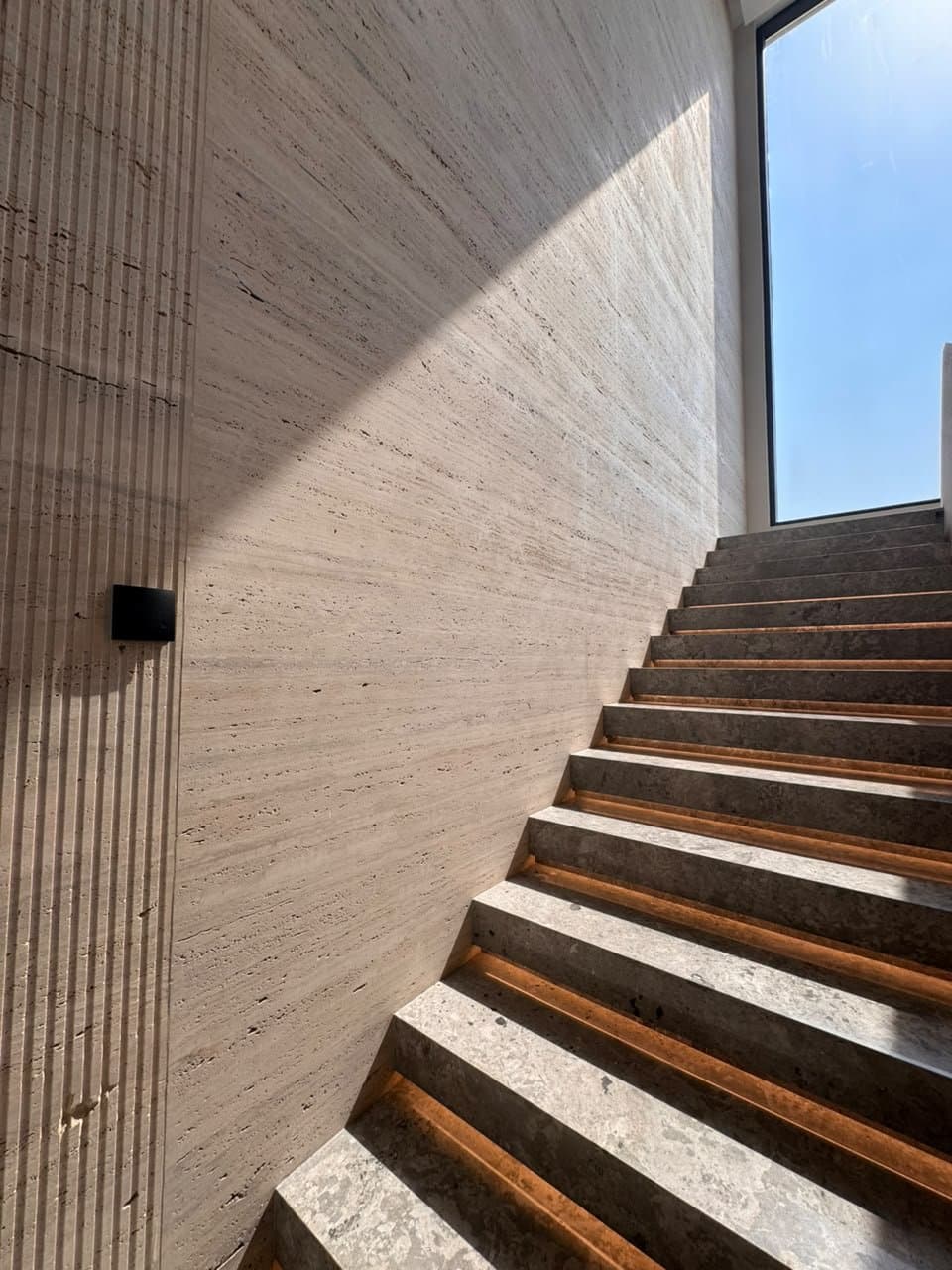 Travertine wall cladding beside a stone staircase, lit by daylight
