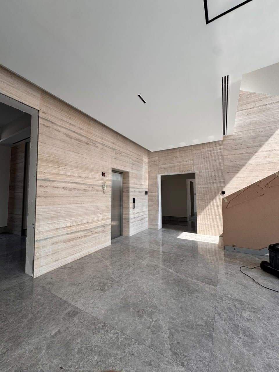 Travertine wall cladding in an entrance hall beside an elevator