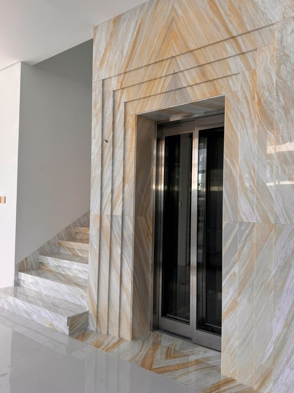 Bookmatched onyx-look marble elevator surround with amber veining