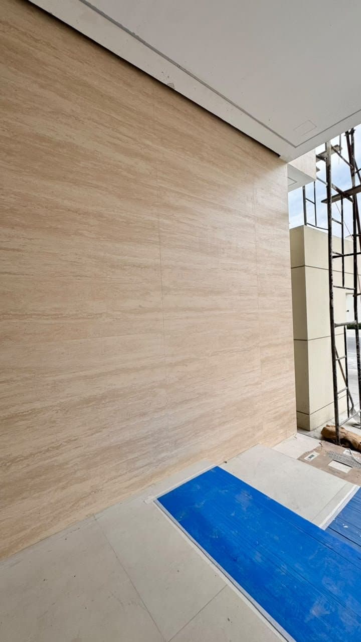 Fluted travertine cladding on an exterior wall, mid-installation