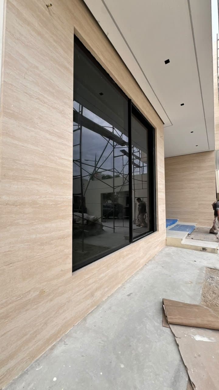 Travertine cladding framing a window on a villa facade