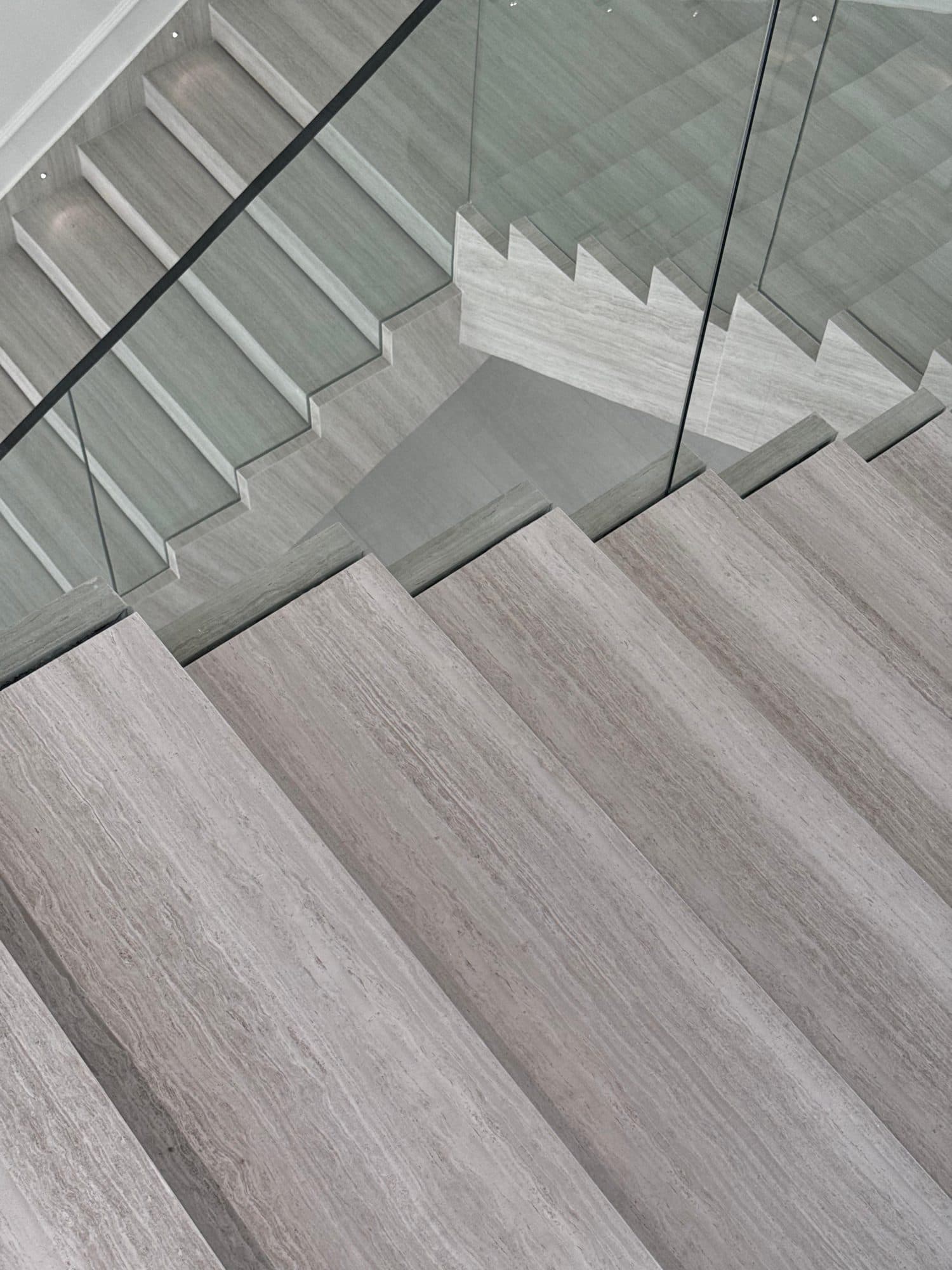 Travertine staircase with glass railing, seen from above
