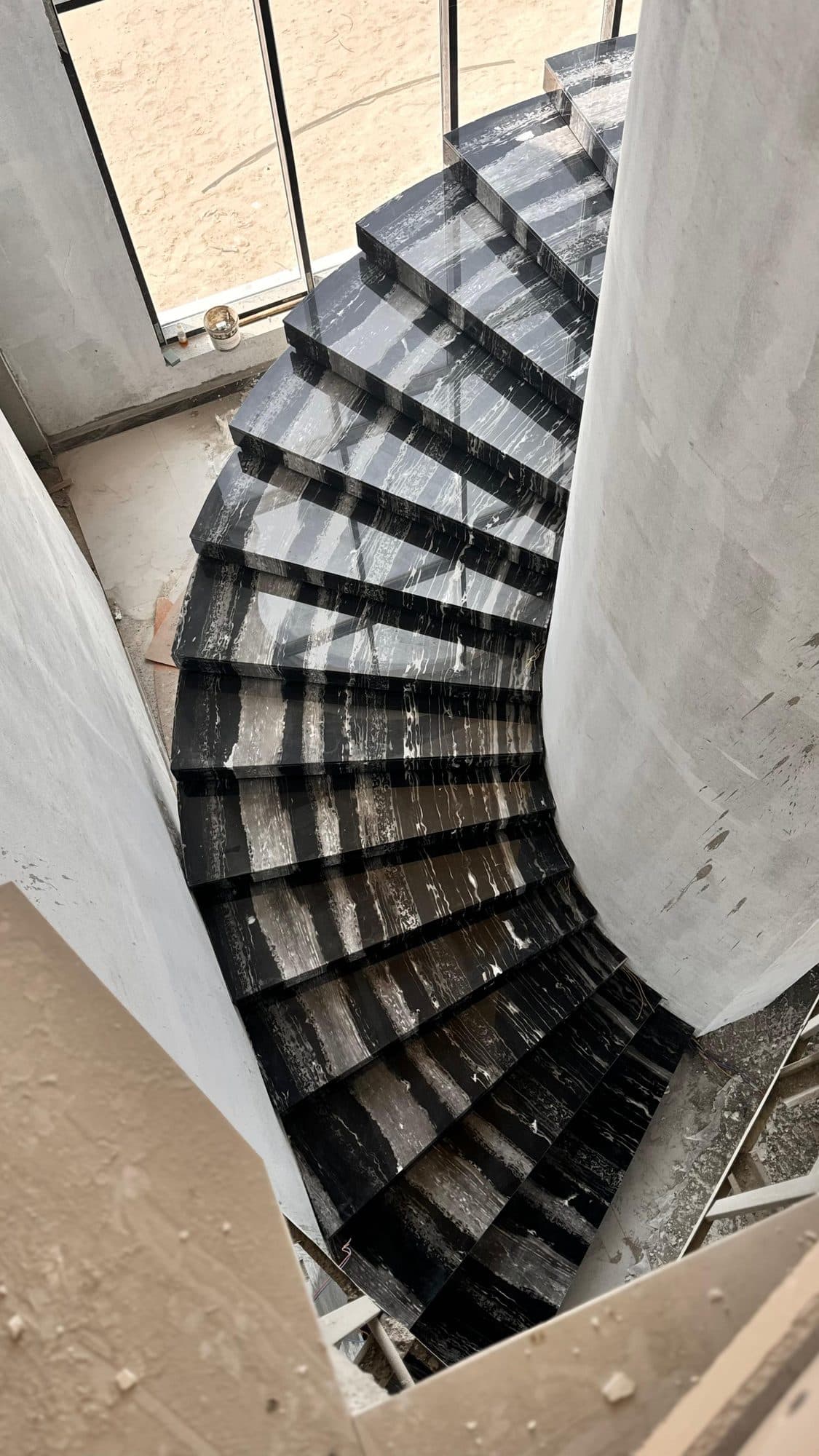 Curved black and white marble staircase under construction