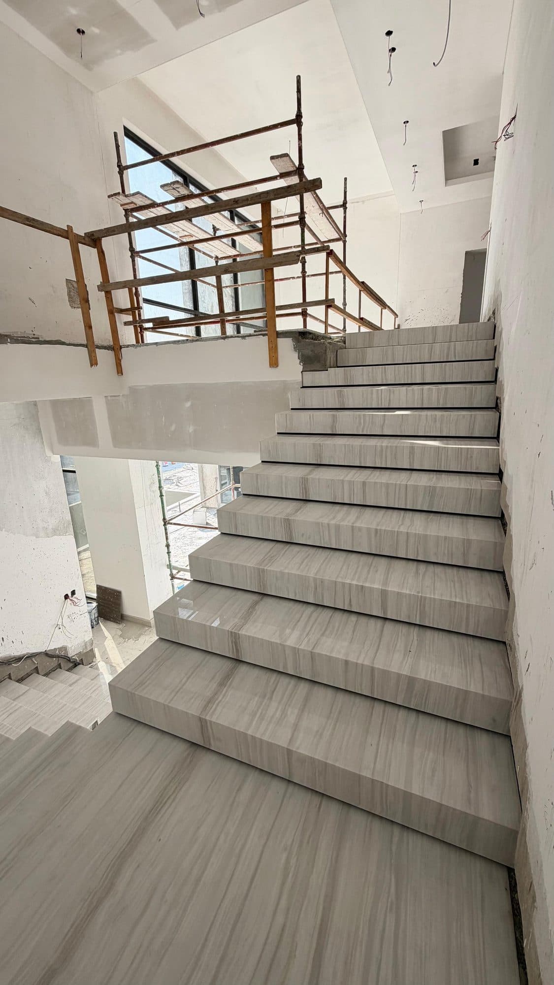Marble staircase installation with scaffolding in an unfinished stairwell