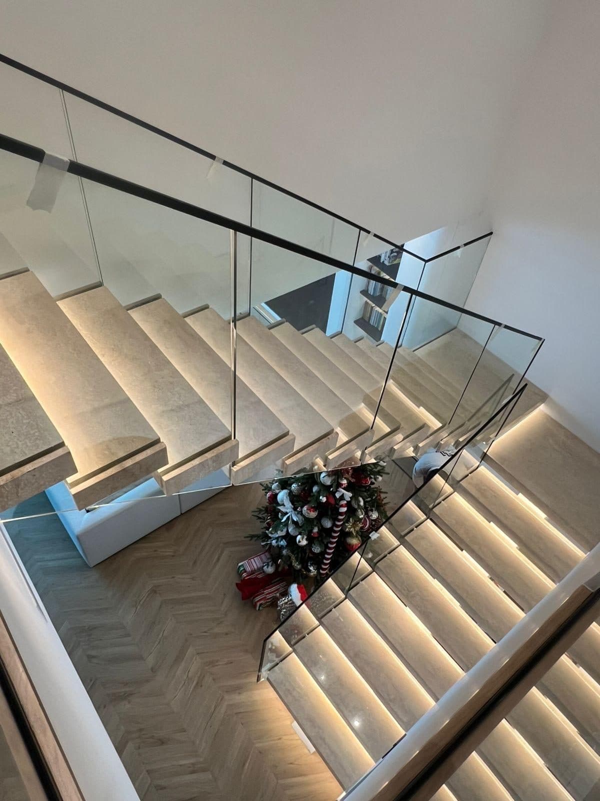 Floating marble staircase with glass balustrade and herringbone floor