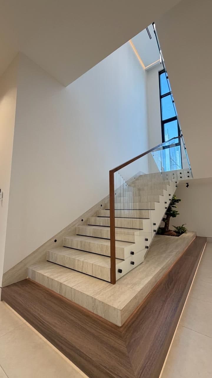 Travertine staircase with wood-trimmed glass balustrade