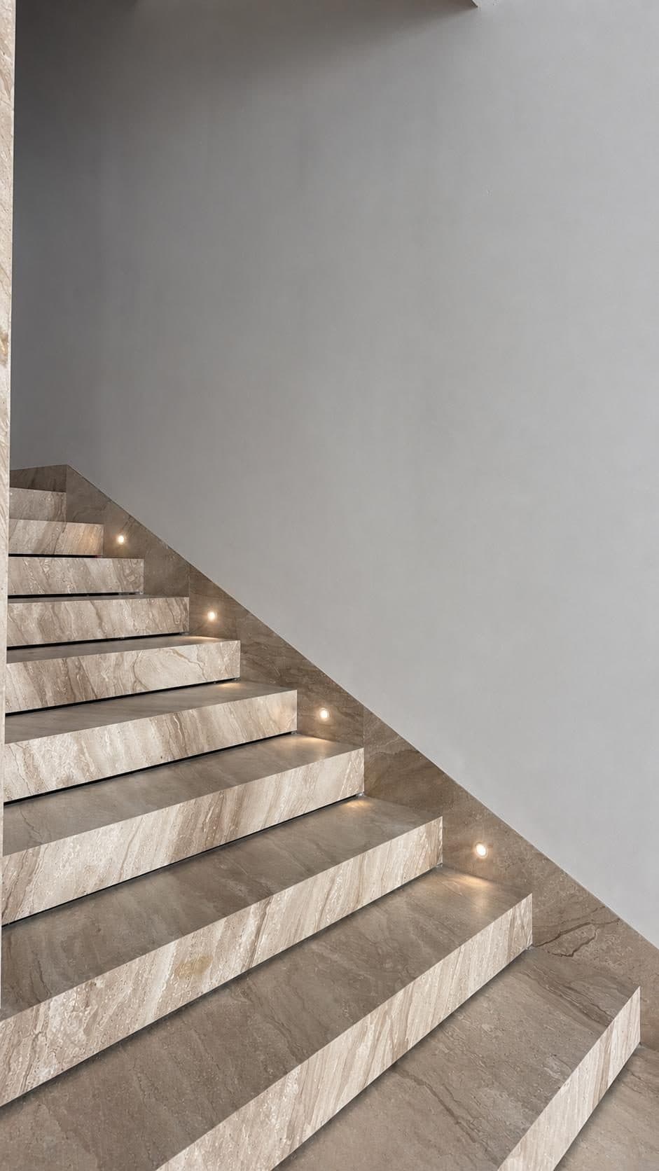 Travertine staircase with recessed step lighting